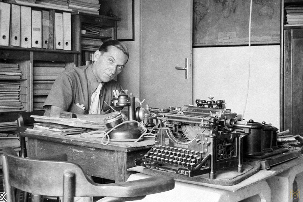 An office worker focused at his typewriter, surrounded by filing cabinets - France, 1940s.