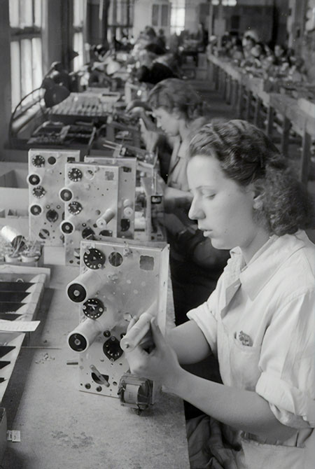 Technicians assembling equipment at a long workbench - care, method and attention repeated in every gesture.