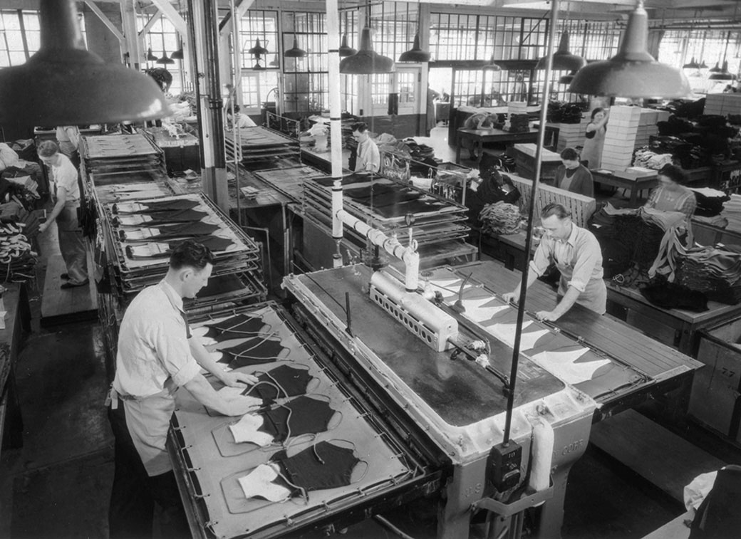 Workers preparing and packaging food at a long counter - method, consistency and attention repeated at every step.